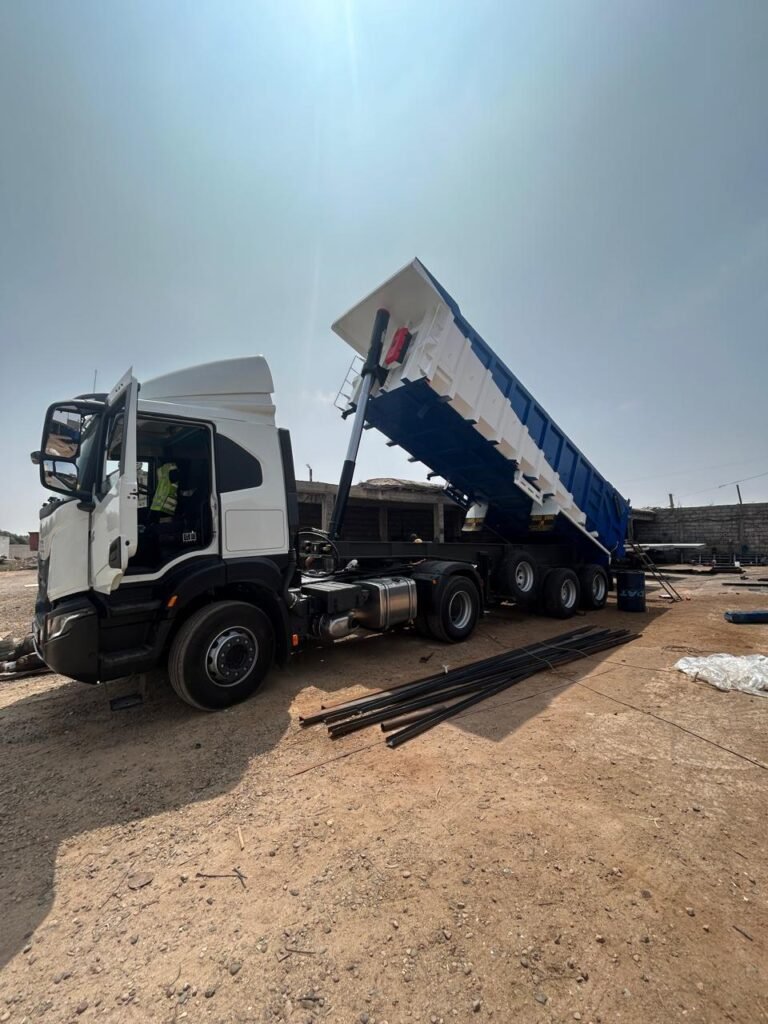 Camion avec benne bleue et blanche en position basculée dans l’atelier Souss Benne